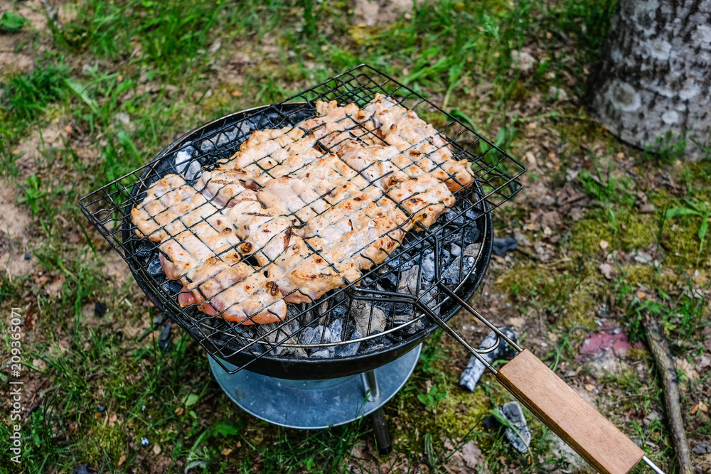 Grilling delicious variety of meat on barbecue charcoal grill. Grilling  food on a weber type small cheap BBQ grill at home. foto de Stock | Adobe  Stock