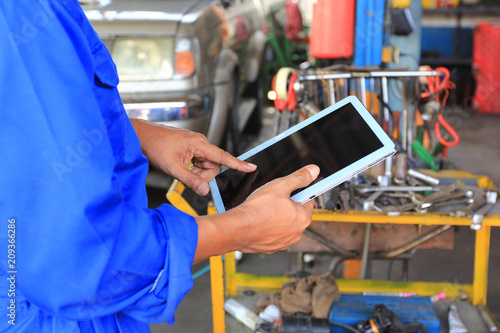 Car mechanic holding digital tablet in auto repair service. © Monthira