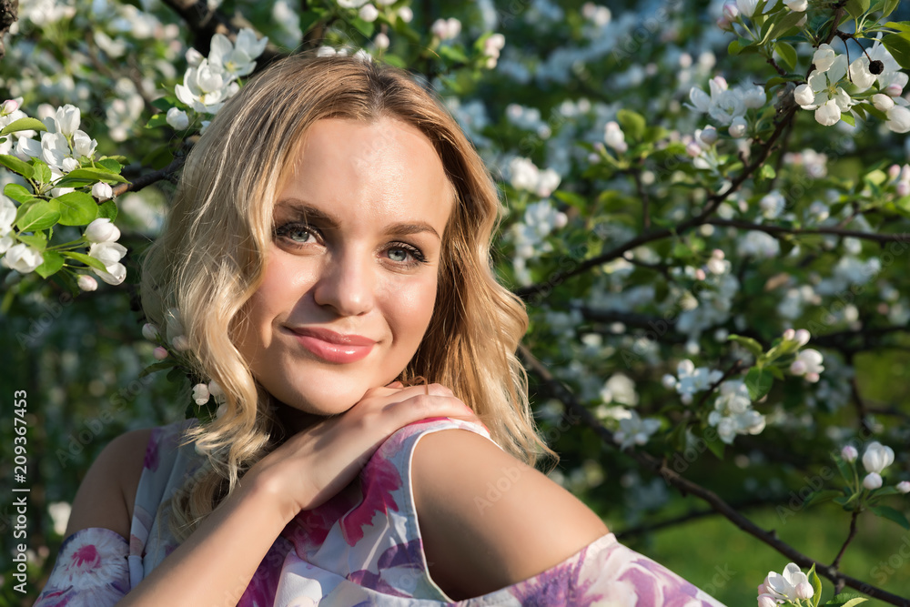 Naklejka premium A girl with light wavy hair near blossoming trees in the park