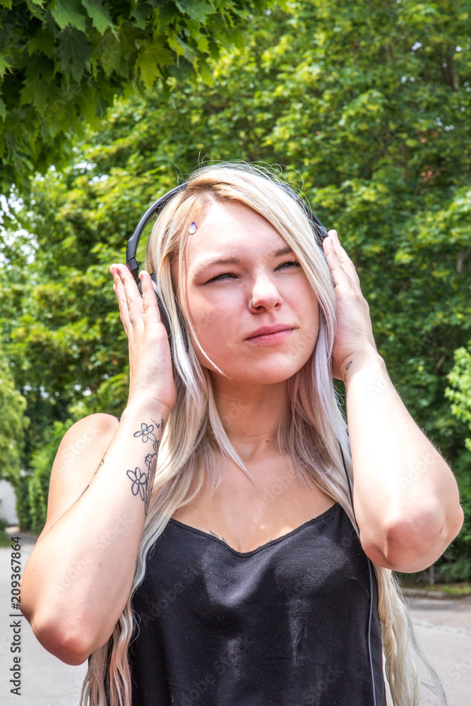 Junge blonde Frau im Freien mit Kopfhörern