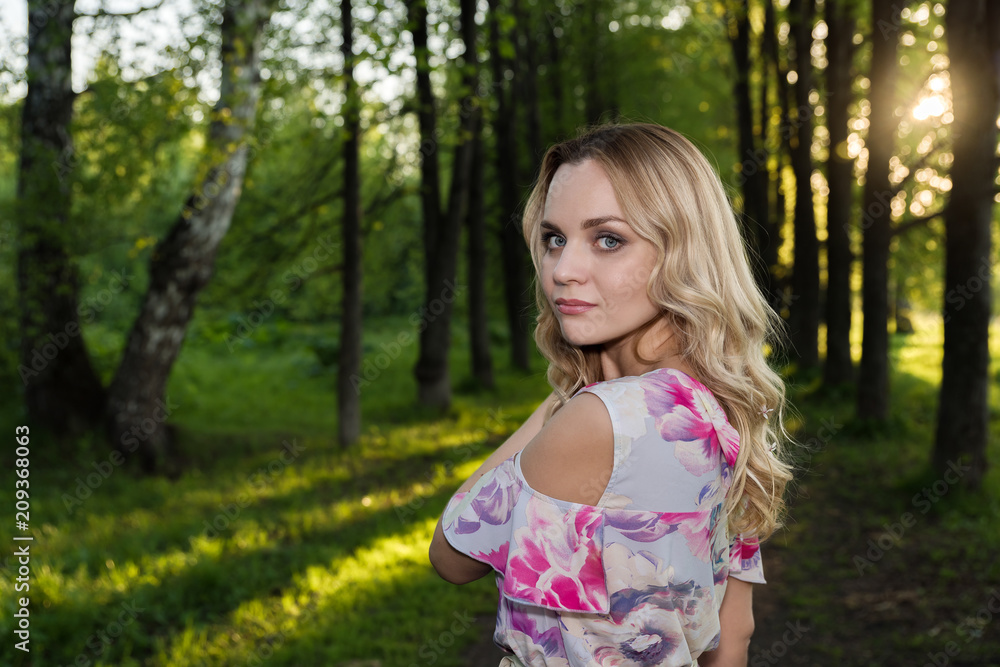 Girl with light wavy hair against the background of trees in the park Girl with light wavy hair against the background of trees in the park