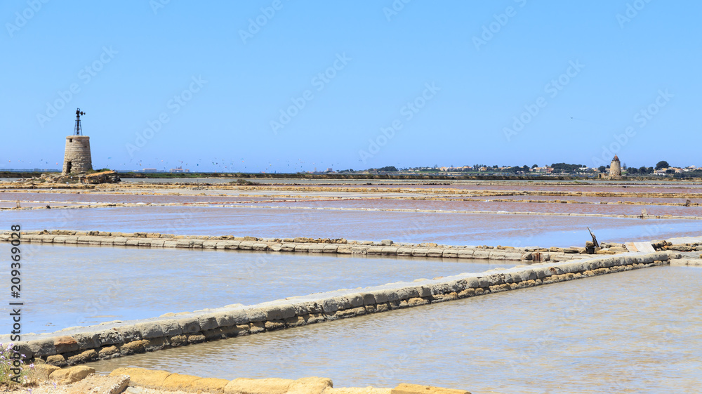 Windmills raising water and flats in which water is evaporated to obtain salt in salines near Trapani, Sicily, Italy