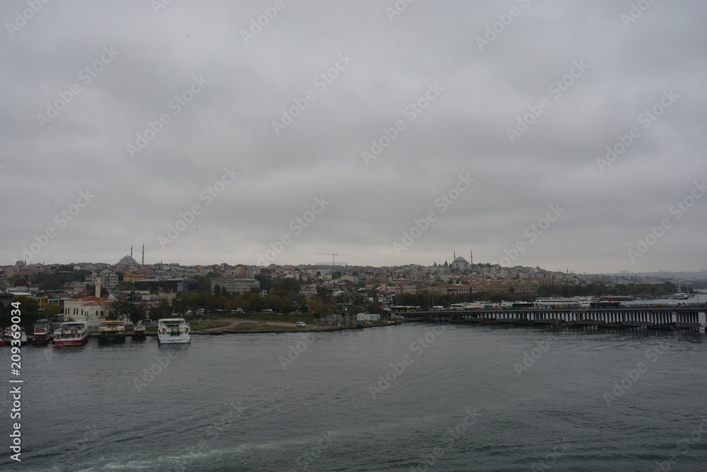 against the background of a gray sky with clouds overlooking the houses, the water and the bridge