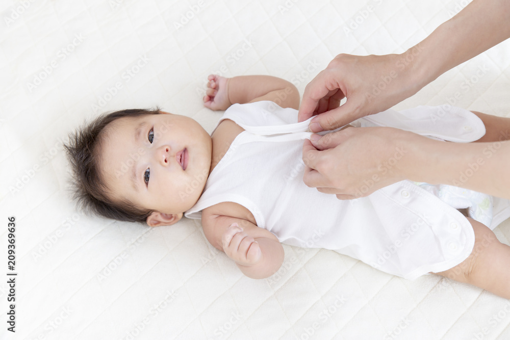 新生児の着替えをする母の手、育児イメージ