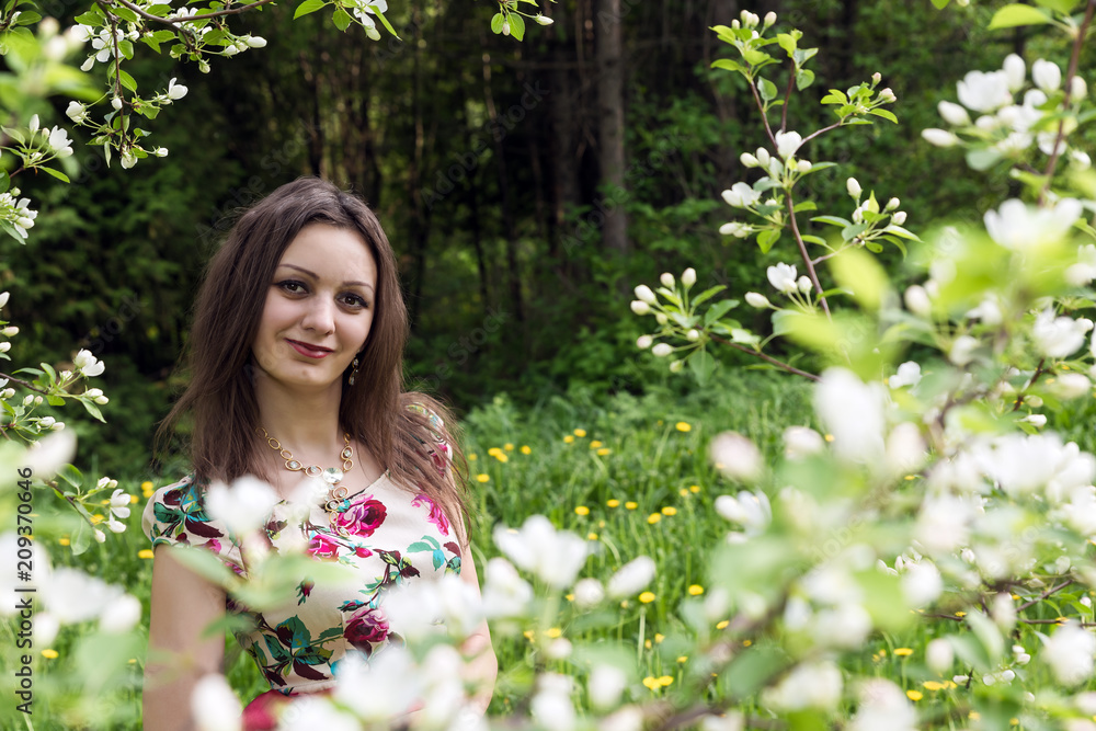 A girl with dark hair against the background of blooming trees in the park A girl with dark hair against the background of blooming trees in the park