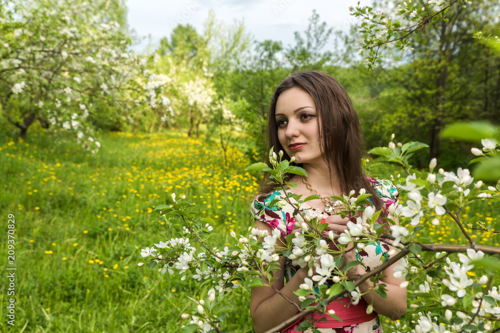 A girl with dark hair against the background of blooming trees in the park A girl with dark hair against the background of blooming trees in the park