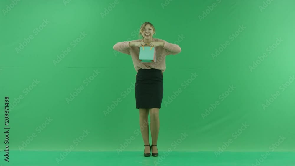 Pretty laughing shopping woman with shopping bags. Female shopper holding shopping bags front on green background in studio. Pretty laughing shopping woman with shopping bags. Female shopper holding shopping bags front on green background in studio.