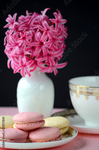 Bright pink hyacinth with French macarons, cup of coffee and gold black stationery. Female and lifestyle business and work from home concept. Spring theme. 