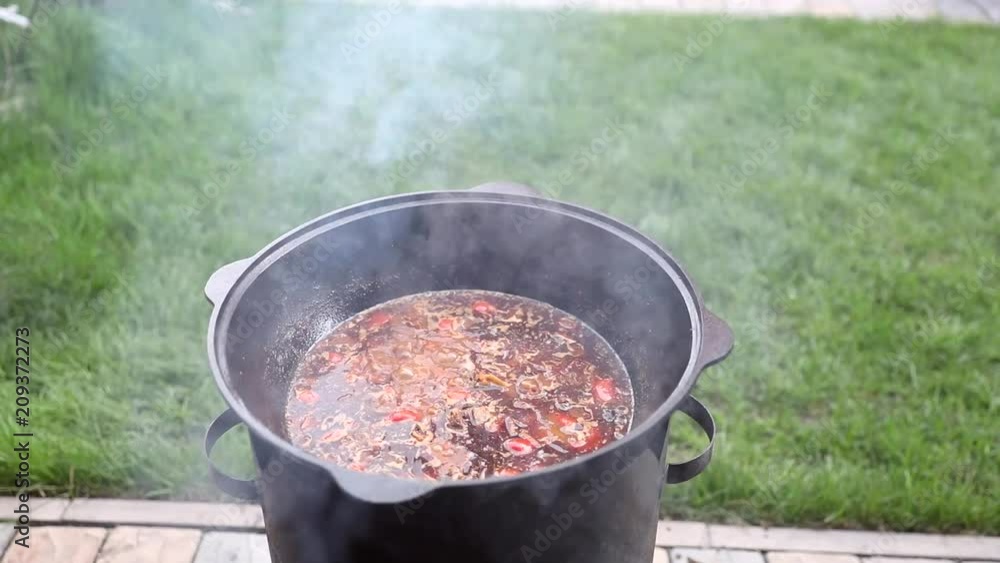 Soup in a cauldron made from vegetables and meat, in a cauldron on the nature. The man is stirring the soup in a saucepan. Soup in a cauldron made from vegetables and meat, in a cauldron on the nature. The man is stirring the soup in a saucepan.