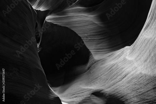 Rolling Light in Slot Canyon: Smooth shapes, rich contrasts in this black and white photograph deep within a slot canyon. Suitable for the travel industry, business offices, and hotel lobbies. 