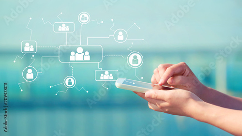 Foto Social Connections with person holding a smartphone in front of modern building