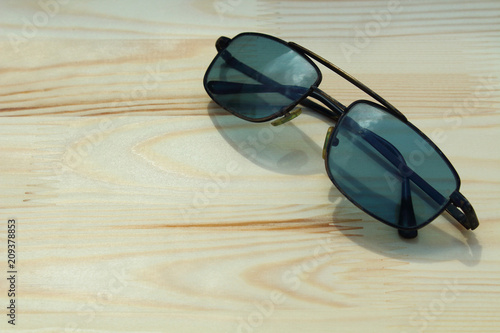 Old black sunglasses lying on a new wooden board. Close-up. Background.