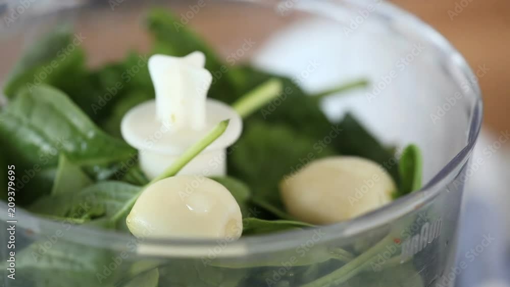 Chef adds water into the blender with spinach. Chef adds water into the blender with spinach.