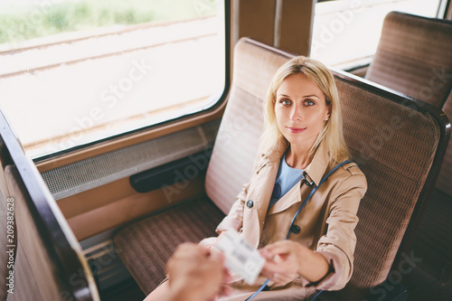 Travel and transport. Young pretty woman giving ticket to train conductor.