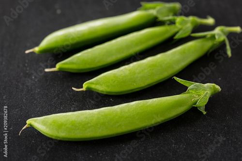 Freshly picked snow peas on a black background.