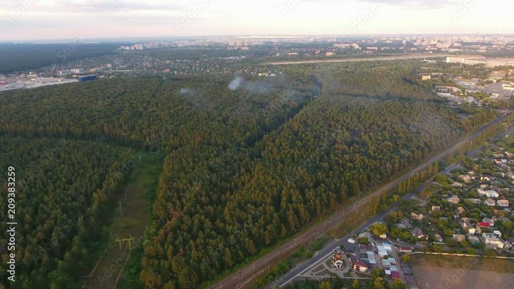 A picturesque bird`s eye view of the outskirts of Kiev with a high pine wood, a straight highway and numerous small houses in summer A picturesque bird`s eye view of the outskirts of Kiev with a high pine wood, a straight highway and numerous small houses in summer