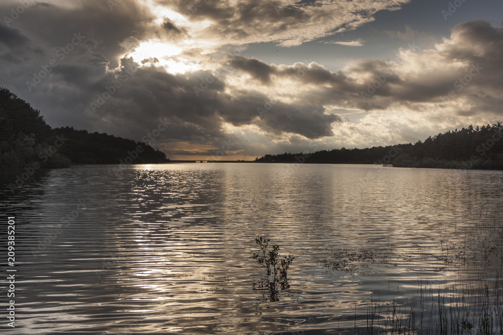 sunset in the Revenga reservoir, Segovia, Spain. Golden and silver tones with reflections in the water. Calm scene.
