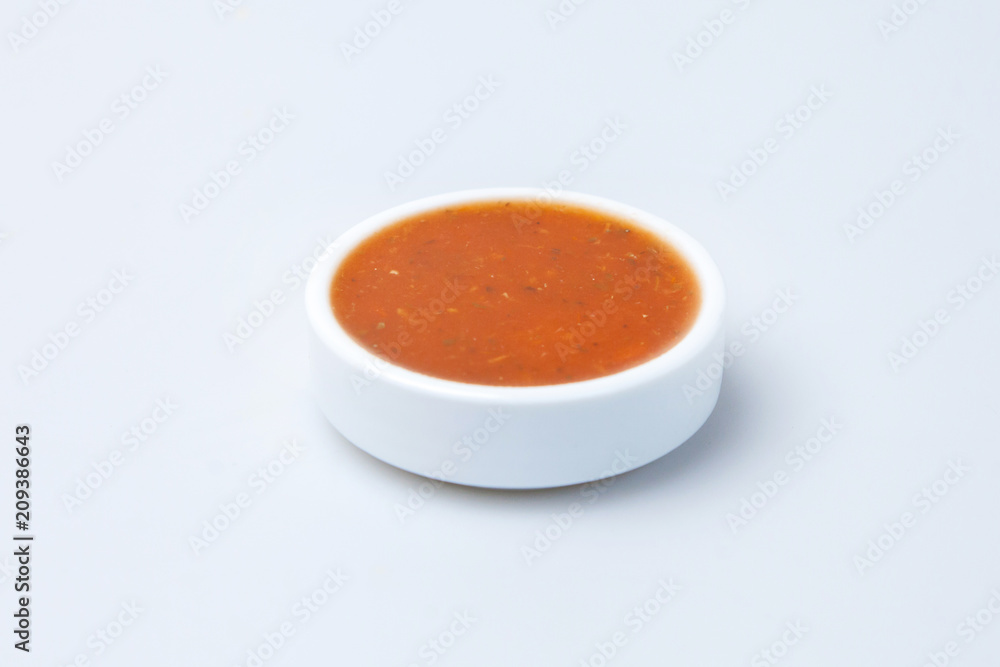 a plate of tomato sauce stands on the table on a white background a plate of tomato sauce stands on the table on a white background