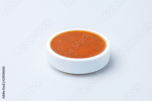 a plate of tomato sauce stands on the table on a white background