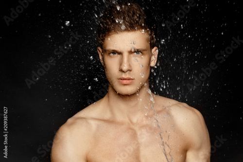 Wet guy portrait in water splash and drops