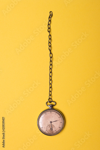 Old pocket watch on yellow background 