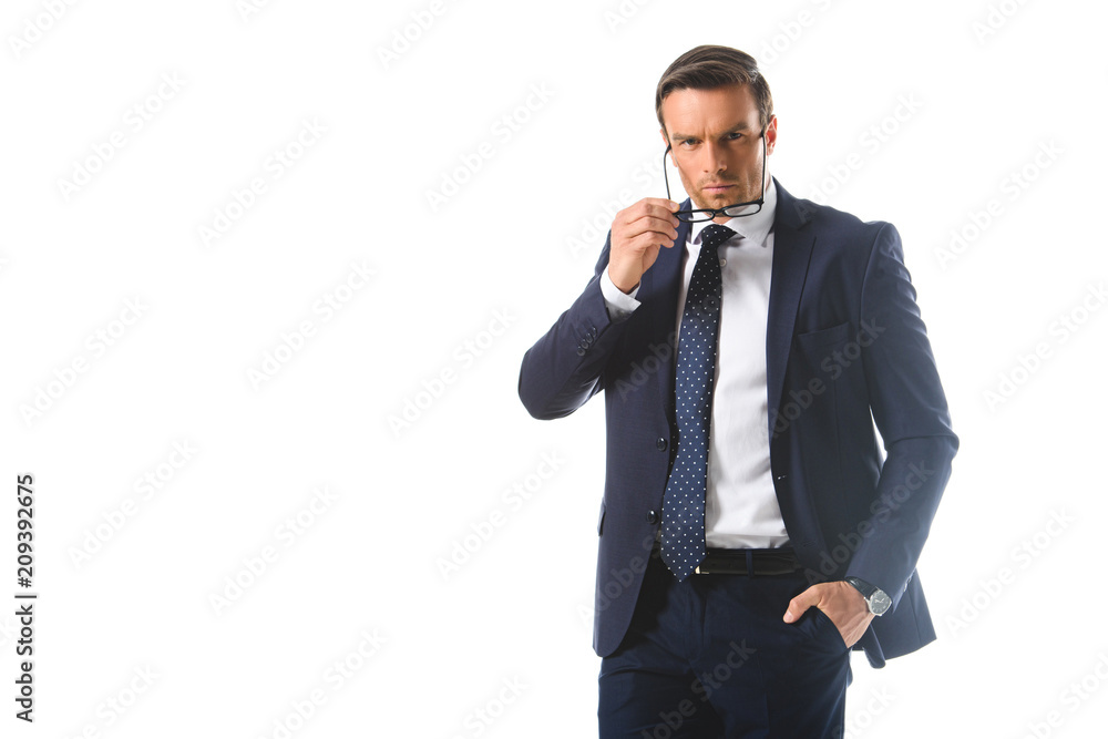 serious businessman with hand in pocket putting on eyeglasses isolated on white background serious businessman with hand in pocket putting on eyeglasses isolated on white background