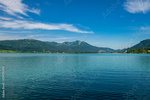 Türkiser See in Österreich mit Bergen im Hintergrund und Wolken am blauen Himmel