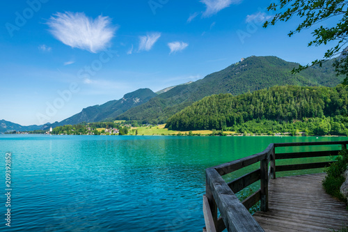 Steg entlang am See in Österreich welcher Wolfgangsee genannt wird mit Berge im Hintergrund und Wolken am Himmel