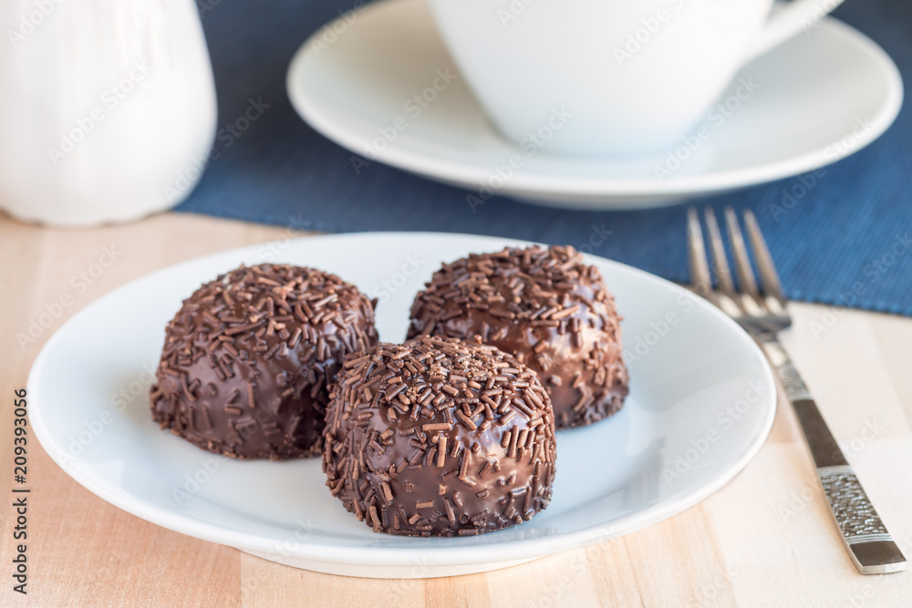 Swedish sweets Arrack balls, made from cookie crumbs, cocoa, butter and coconut wine Arrack flavour, on wooden table with a cup of tea, horizontal Swedish sweets Arrack balls, made from cookie crumbs, cocoa, butter and coconut wine Arrack flavour, on wooden table with a cup of tea, horizontal