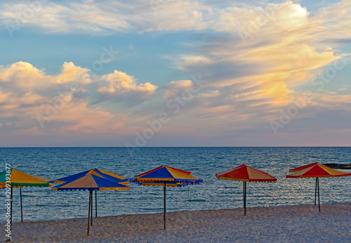 Sea beach with umbrellas against the sky before sunset