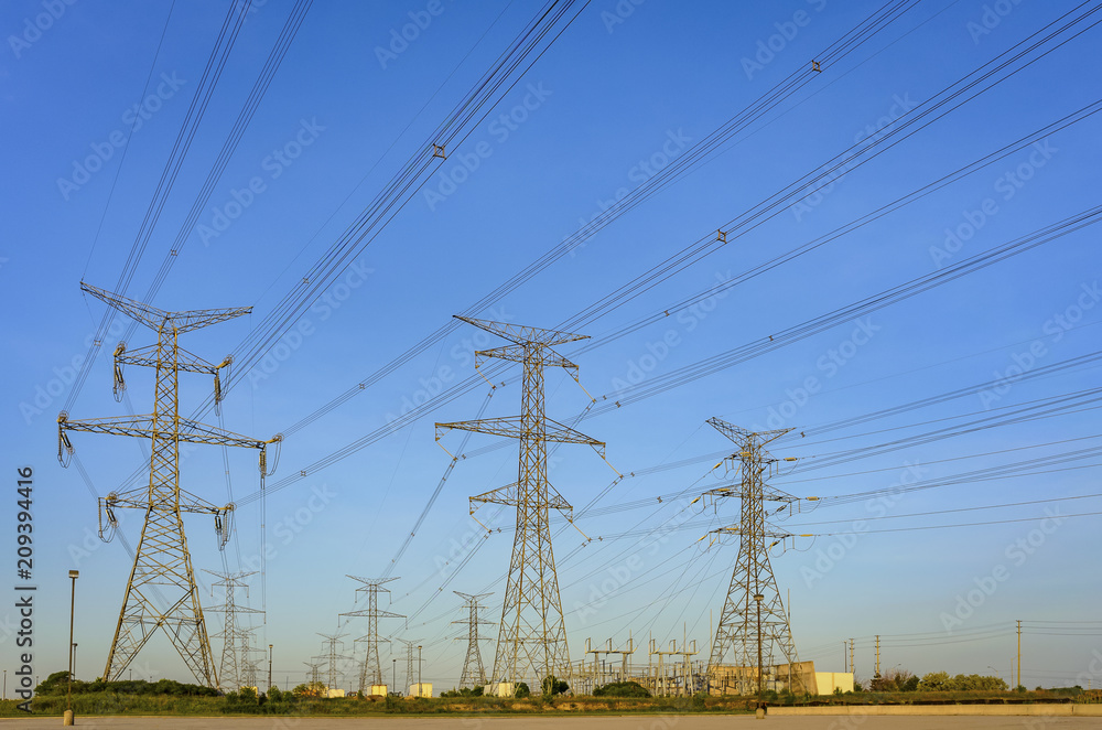 Electrical poles and power lines in a  rural North American area at midday with a blue sky in the background
