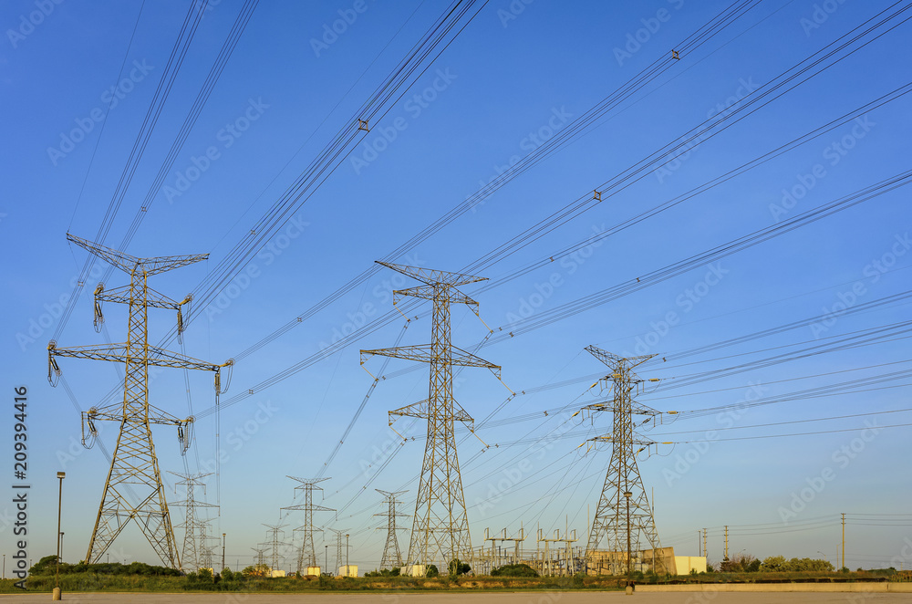 Electrical poles and power lines in a rural North American area at midday with a blue sky in the background Electrical poles and power lines in a rural North American area at midday with a blue sky in the background