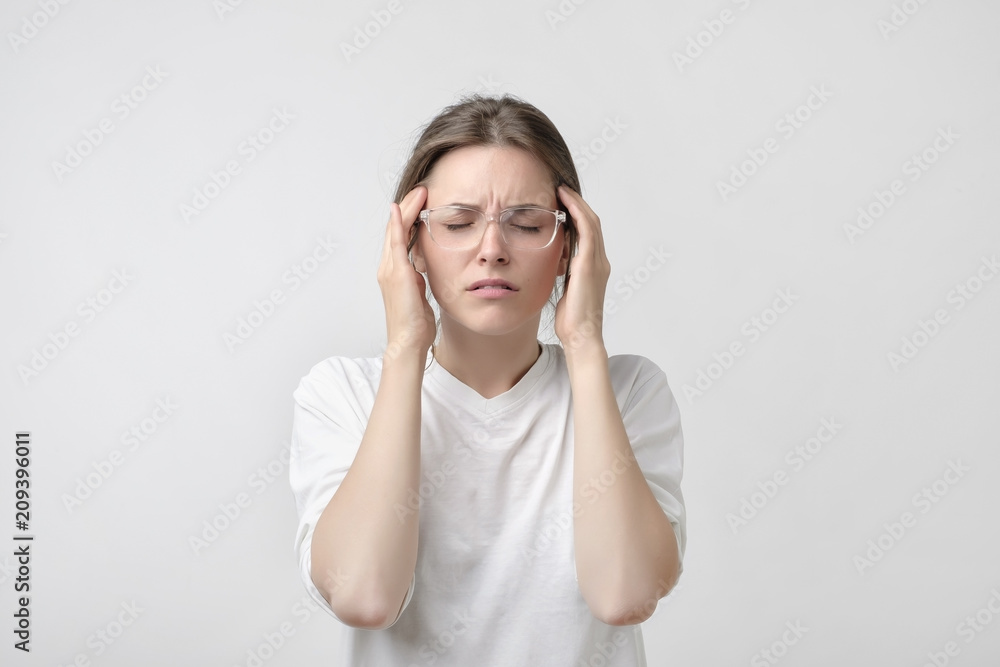 European girl in white t-shirt suffers from terrible headaches and compresses the head with fingers. European girl in white t-shirt suffers from terrible headaches and compresses the head with fingers.