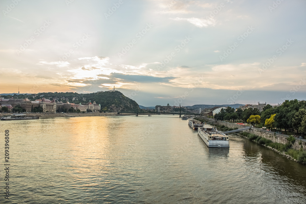 evening urban city scape of waterfront with river and ships in sunset time with sun rays and soft colors