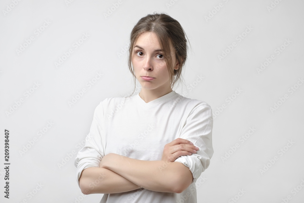 Portrait of an upset unsatisfied european woman standing with arms crossed and looking at camera Portrait of an upset unsatisfied european woman standing with arms crossed and looking at camera