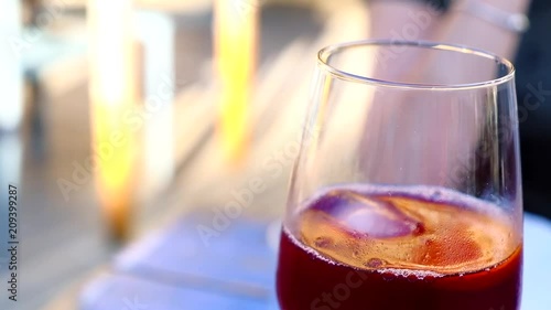Close-up of orange slice falling into the glass with sangria. Spanish summer alcohol drink of red wine, ice and fruits.