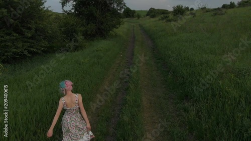 Cheerful young girl walking barefoot on a country road. aerial viewl. Taken on Mavik Air 4k 100kbps photo