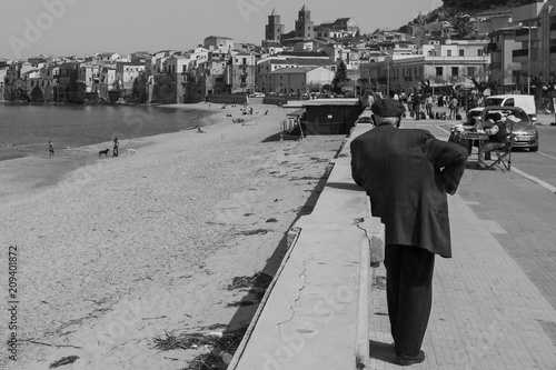 CEFALU, PALERMO, SICILY. April 2017: black and white shoot of old time Sicilian rural city. Old man wearing typical coppola hat, and fisherman houses facing the sea. photo