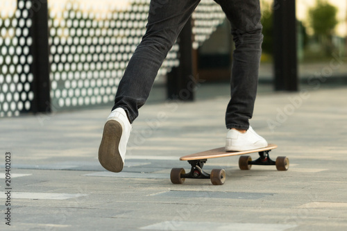 Man skateboarder riding longboard in the city  outdoors  cropped image. Leisure  healthy lifestyle  extreme sports concept