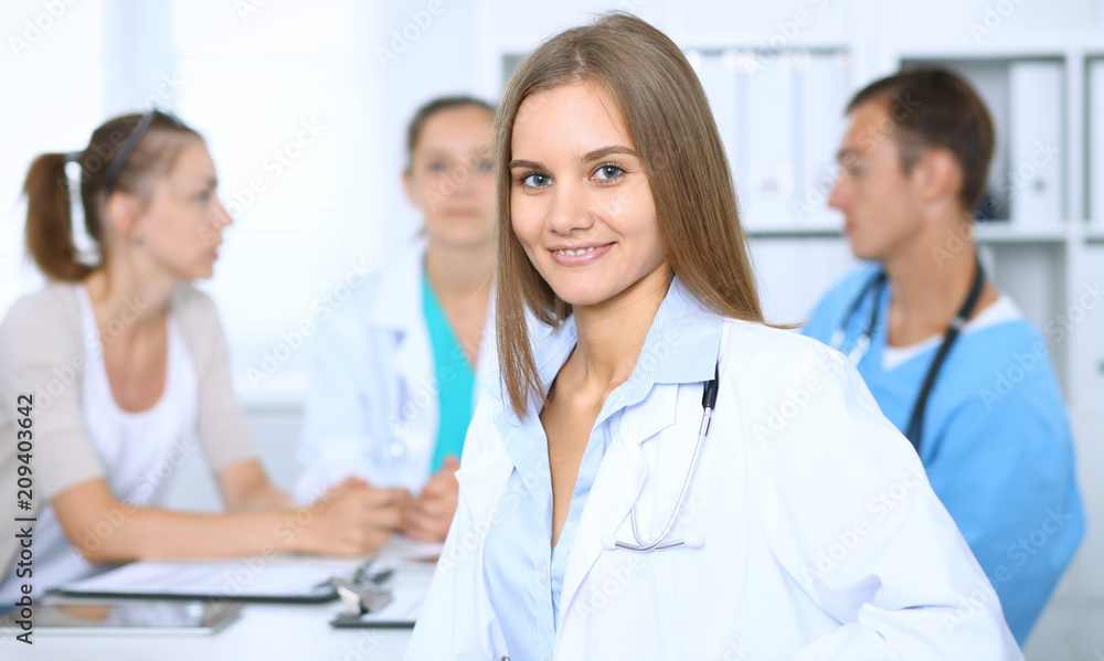 Happy doctor woman with medical staff at the background in hospital office Happy doctor woman with medical staff at the background in hospital office
