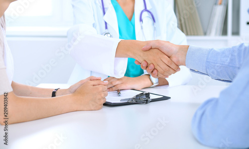 Doctor and family couple of patient are discussing something  just hands at the table. Medicine concept