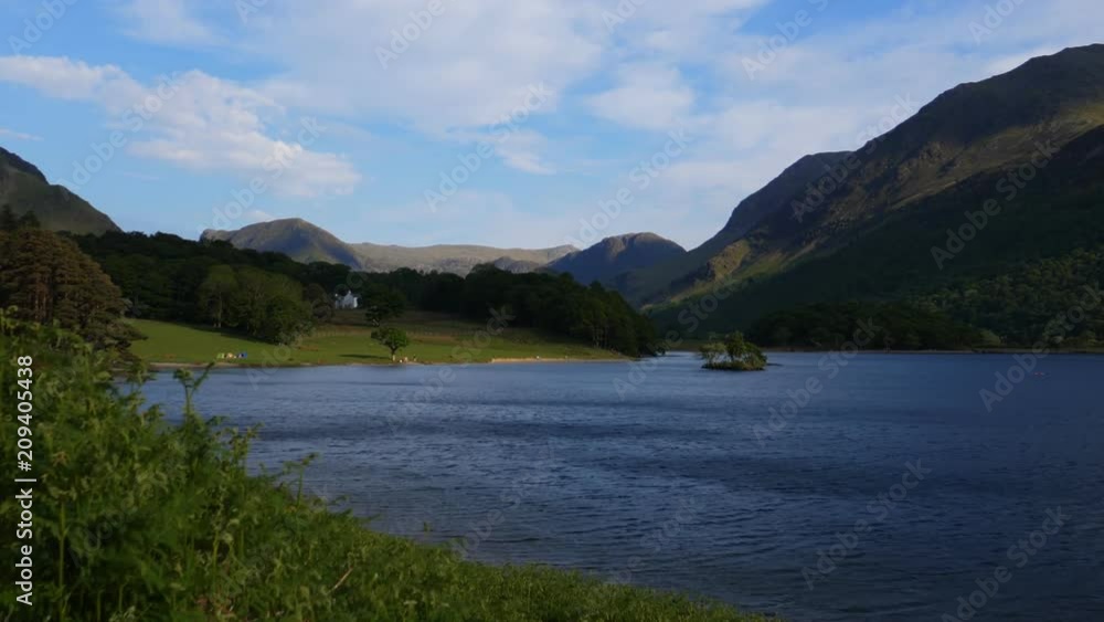 Stunning scenery of Crummock Water and surrounding mountains in Lake District in England, United Kingdom, blurry foreground grass Stunning scenery of Crummock Water and surrounding mountains in Lake District in England, United Kingdom, blurry foreground grass