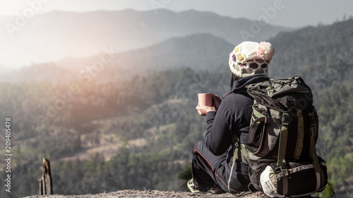 woman traveler drinks coffee with a view of the mountain landscape in the morning.