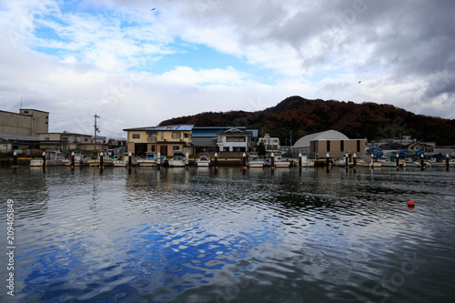 Boats docked at harbor on the Sea of Japan with blue reflected sky in the water