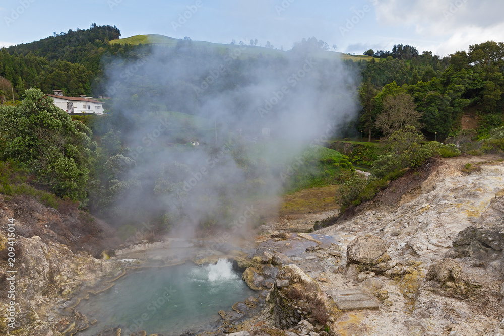 Hot spring surrounded by volcanic terrain and mountainous landscape in Furnas, Azores, Portugal. Summer landscape of Azorean village on a cloudy day. Hot spring surrounded by volcanic terrain and mountainous landscape in Furnas, Azores, Portugal. Summer landscape of Azorean village on a cloudy day.