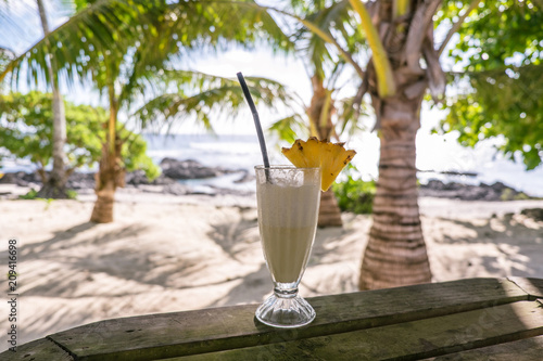 Tropical pina colada cocktail drink with pineapple garnish in glass with straw at exotic beach at Lefaga, Upolu Island, Samoa, South Pacific