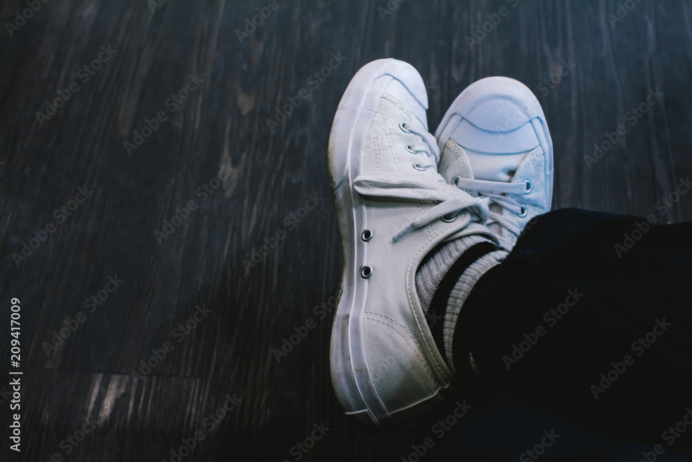 Fototapeta premium Man wearing white sneakers in black trousers sitting on coffee shop,Vintage tone.Selective focus