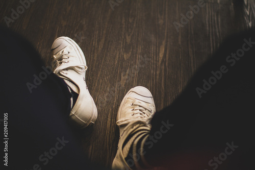 Man wearing white sneakers in black trousers sitting on coffee shop,Vintage tone.Selective focus