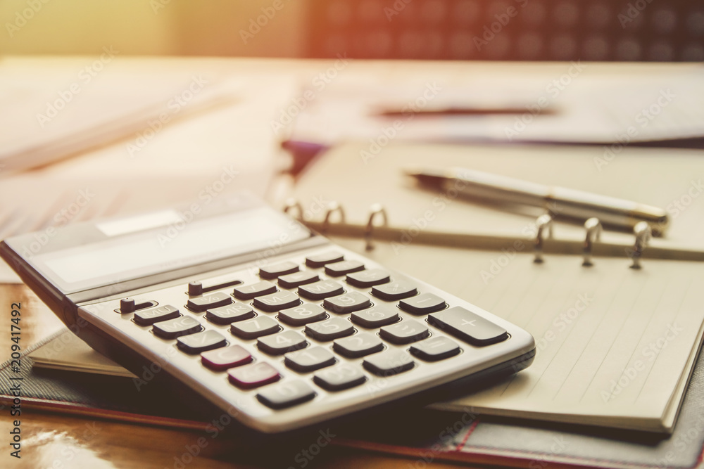 account work calculator, profit and tables on notebook with sunset light. Vintage filter account work calculator, profit and tables on notebook with sunset light. Vintage filter