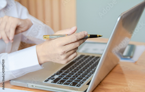 Business woman hands holding pen and using laptop with blank screen on desk in cafe.